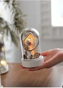Close-up of a Christmas glass globe with wooden cabin scenes and warm LED glow