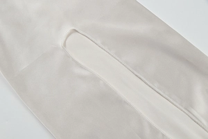 Detail of precise overlock stitching and smooth satin fabric on a light grey dress