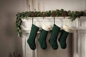 Detail of dark green and cream knitted Christmas stockings hanging on a white fireplace