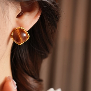 Gros plan d'un mannequin portant des boucles d'oreilles dorées avec résine œil de chat