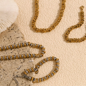 Flat lay of gold and two-tone braided link necklaces on natural stone and coral