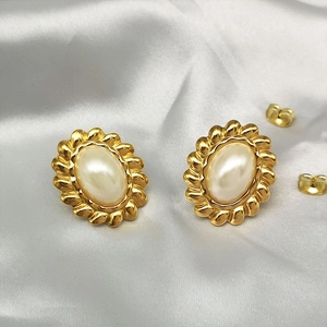 Detail of vintage 18K gold plated stainless steel pearl earrings on white silk