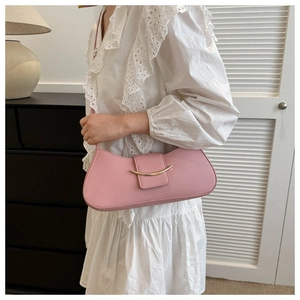 Pink crescent underarm bag with gold metal trim worn by a model in lace dress