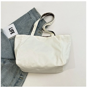 Detailed top view of white canvas tote bag with wide straps and minimalist design