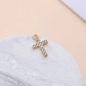 Detailed view of a gold plated cross charm with crystal rhinestones on marble base