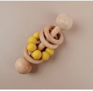 Detail of wooden baby rattle with natural beech rings and yellow silicone beads