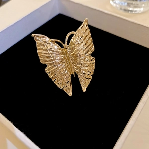 Macro detail of gold-plated butterfly ring with hammered texture on black velvet