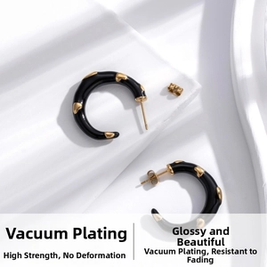 Detail view of black enamel C-shaped earrings with gold heart relief patterns in steel