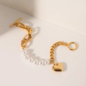 Detail of gold pearl link bracelet featuring a heart pendant and toggle OT clasp