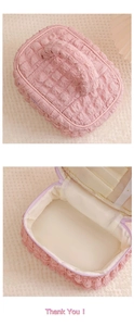 Detail view of pink cream cosmetic bag with handle and internal storage compartments