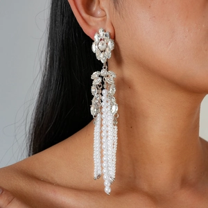 Gros plan de boucles d'oreilles à pompons perles et fleurs avec strass portées par un mannequin