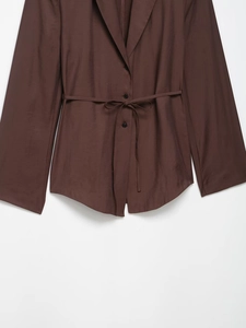 Detail of dark brown blazer waist with button closure and matching fabric belt tie