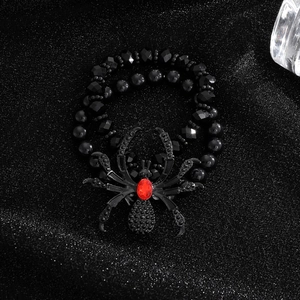 Macro detail of gothic beaded spider bracelet with vibrant red gemstone on black background