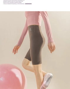 Detail of pink long-sleeve yoga top and brown high-waist shorts with branded logo