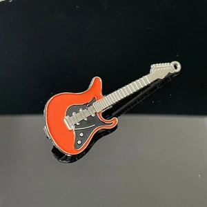 Detailed close-up of a Y2K aesthetic orange and black enamel electric guitar hair clip