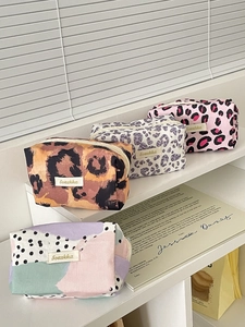 Detail view of four vintage leopard print pouches with zippers and woven logo tags