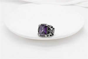 Macro shot of rectangular purple gemstone and retro cross carvings on titanium ring