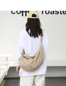 Vista posteriore di una modella con la grande borsa a tracolla beige a mezzaluna