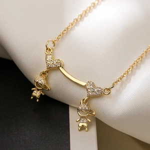 Gold plated boy and girl pendant necklace with zircon accents on a soft background