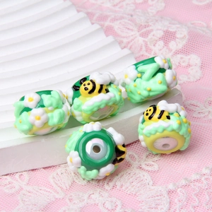 Macro shot of 5 cylindrical acrylic hand-painted beads with bees and white flower patterns