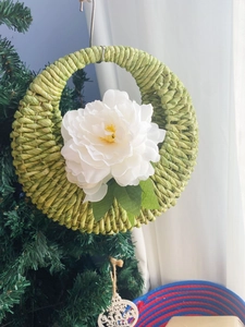 Detail of hand-woven green corn rope wall basket with a delicate white peony flower