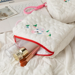 Detail of white quilted cosmetic bag with heart texture, cartoon embroidery and red zipper