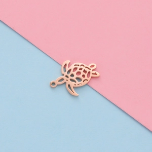 Top view of hollow rose gold turtle pendant on pink and blue background for DIY jewelry
