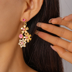 Model wearing gold flower drop earrings with pink and champagne crystals in a close-up view