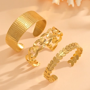 Detailed view of three gold-plated titanium steel bangles with hollow leaf and tree patterns