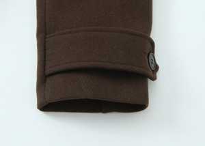 Close-up of the dark brown wool coat sleeve featuring decorative strap and black button detail