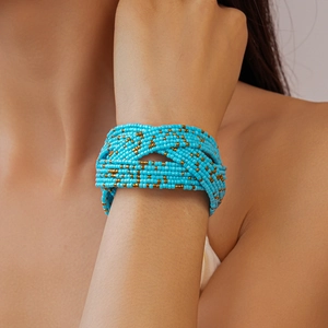 Detail of bohemian multilayer woven bracelet with blue glass beads and golden accents