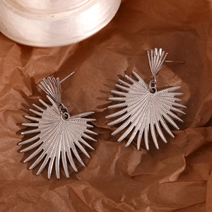 Macro shot of silver radial fan-shaped earrings with metallic sunray texture detail