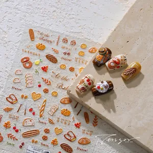 Détail macro de stickers ongles 3D en relief avec motifs boulangerie et citrouille