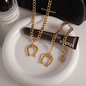 Detail of gold horseshoe pendant bracelets with rhinestones on a chunky curb chain