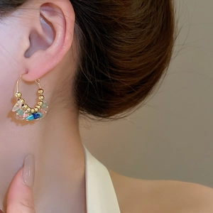 Detail of colorful crushed natural stones and gold beads on bohemian hoop earrings