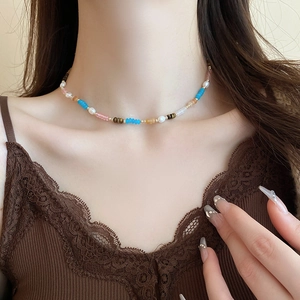 Gros plan d'un collier de perles d'eau douce colorées sur le cou d'une femme