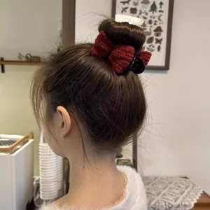Detail of a red knitted bow hair claw clip securing a bun hairstyle from the back view