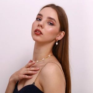 Detail shot of a model wearing a gold butterfly necklace and pearl drop earrings set