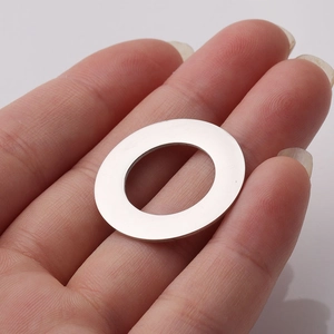 Close-up of polished stainless steel round pendant held on a finger for size