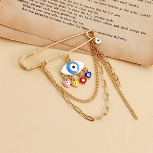 Detailed shot of golden brooch with devil eye pendant, colorful hearts and metal chains