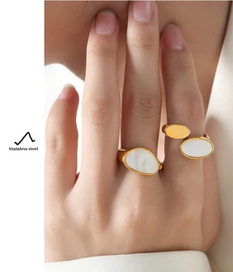 Detail of gold plated stainless steel rings with white mother of pearl on female hand