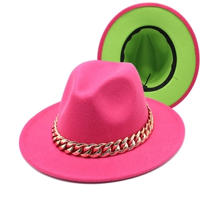 Detail of rose red fedora hat with neon green lining and a thick gold chain decoration