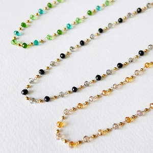 Close-up of faceted crystal beads with golden spacers on hand-wound choker necklaces