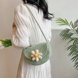 Handwoven green crossbody saddle bag featuring a 3D plush white flower for beach vacations