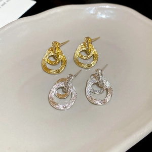 Dettaglio di orecchini intrecciati in oro e argento opaco con accenti di zirconi