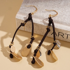 Détail de boucles d'oreilles avec cordon en daim marron et paillettes métalliques dorées