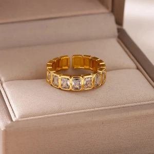 Close-up of golden adjustable ring with baguette-cut zircons on beige jewelry box
