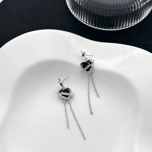 Silver star earrings with black heart stones and long fringe tassel chains on white plate
