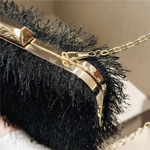 Macro detail of black fringe texture with elegant gold metal trim on luxury evening clutch