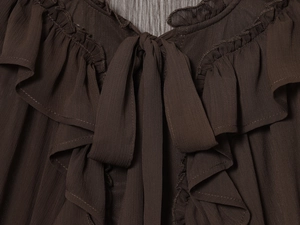 Close-up of dark brown layered ruffle blouse with a tie-up V-neck and crepe fabric detail